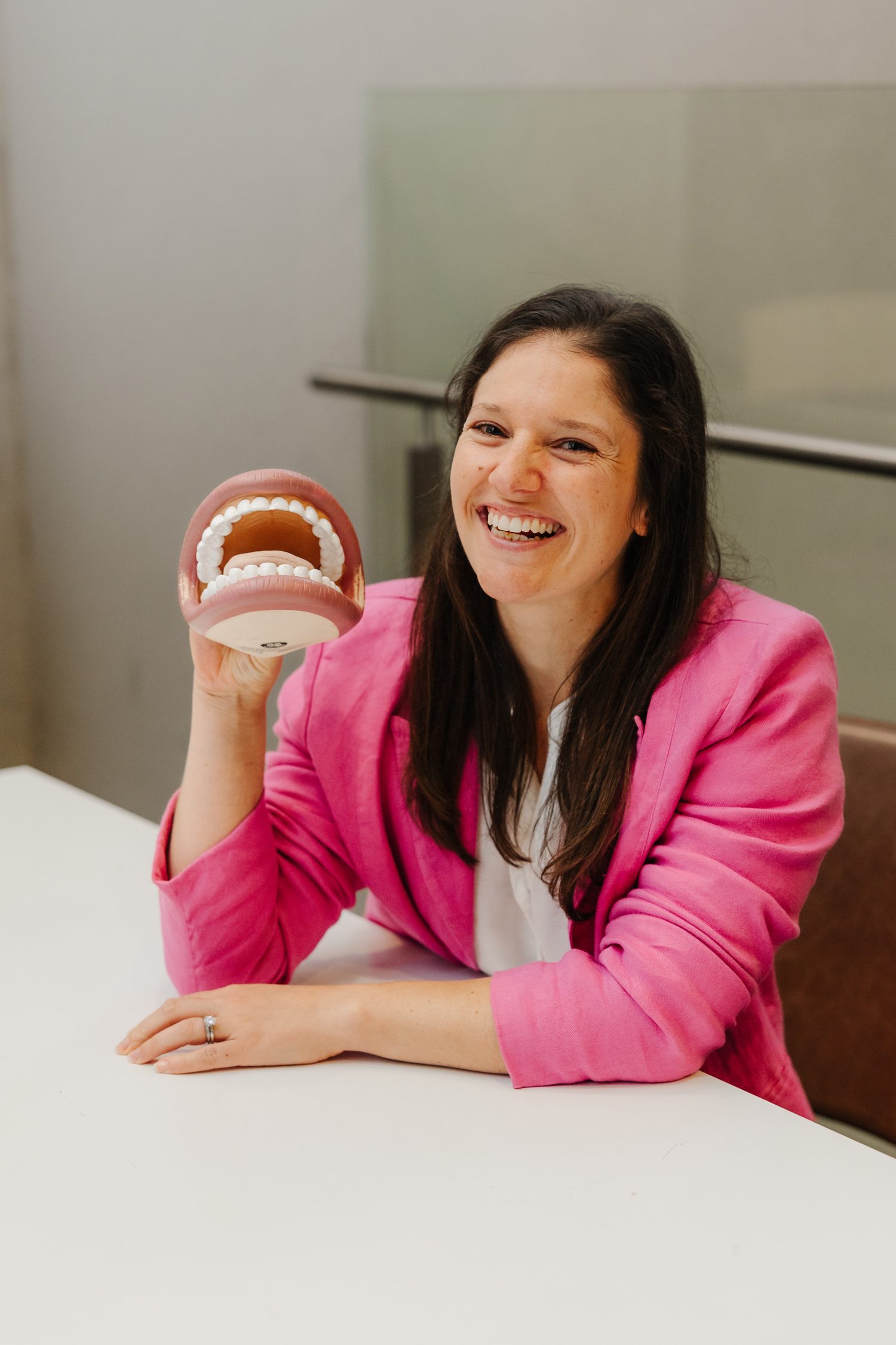 Nicole Petrin, Sydney speech and language pathologist, smiling and holding a model of teeth